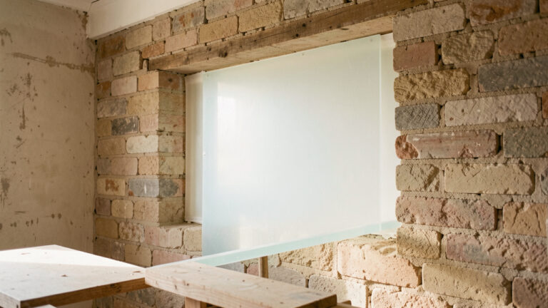 Panneaux d’aérogel translucides posés en couche mince dans le mur d’un bâtiment ancien, illustrant une rénovation thermique qui conserve l’espace intérieur.